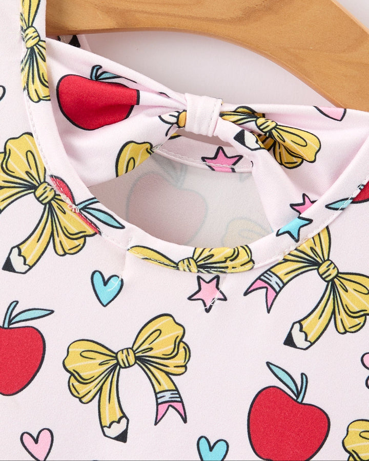 Close-up of a white shirt with colorful bow and apple patterns.