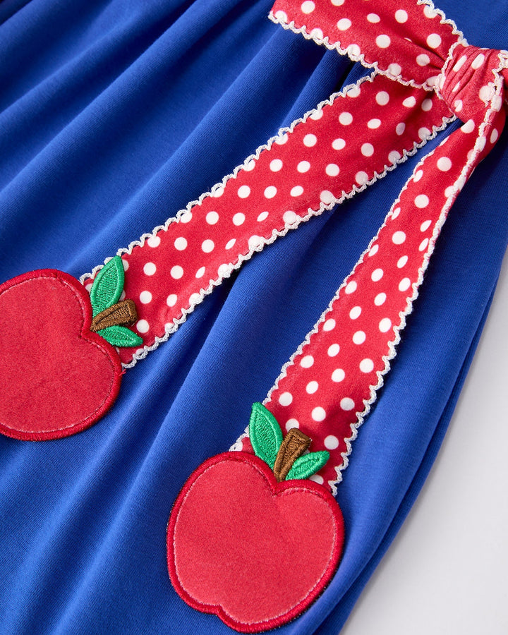 Red dress with polka dot trim and apple appliqués on a blue fabric background