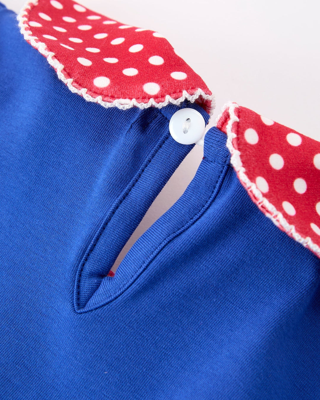 Blue garment with red and white polka dot trim on a white background