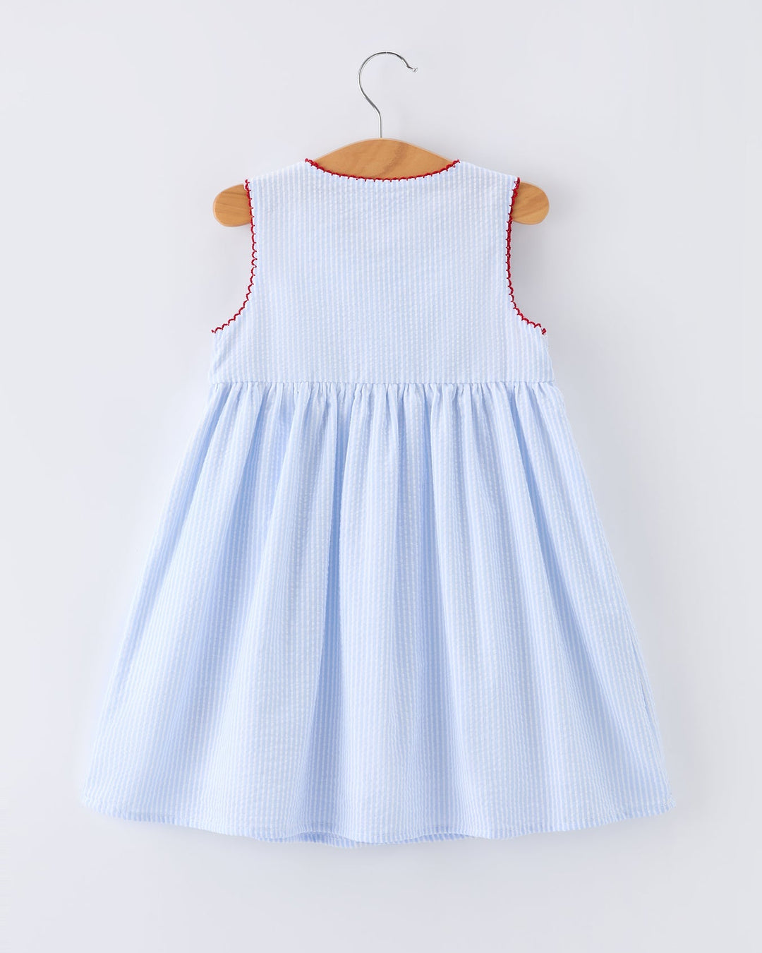 Light blue dress with red trim on a hanger against a white background