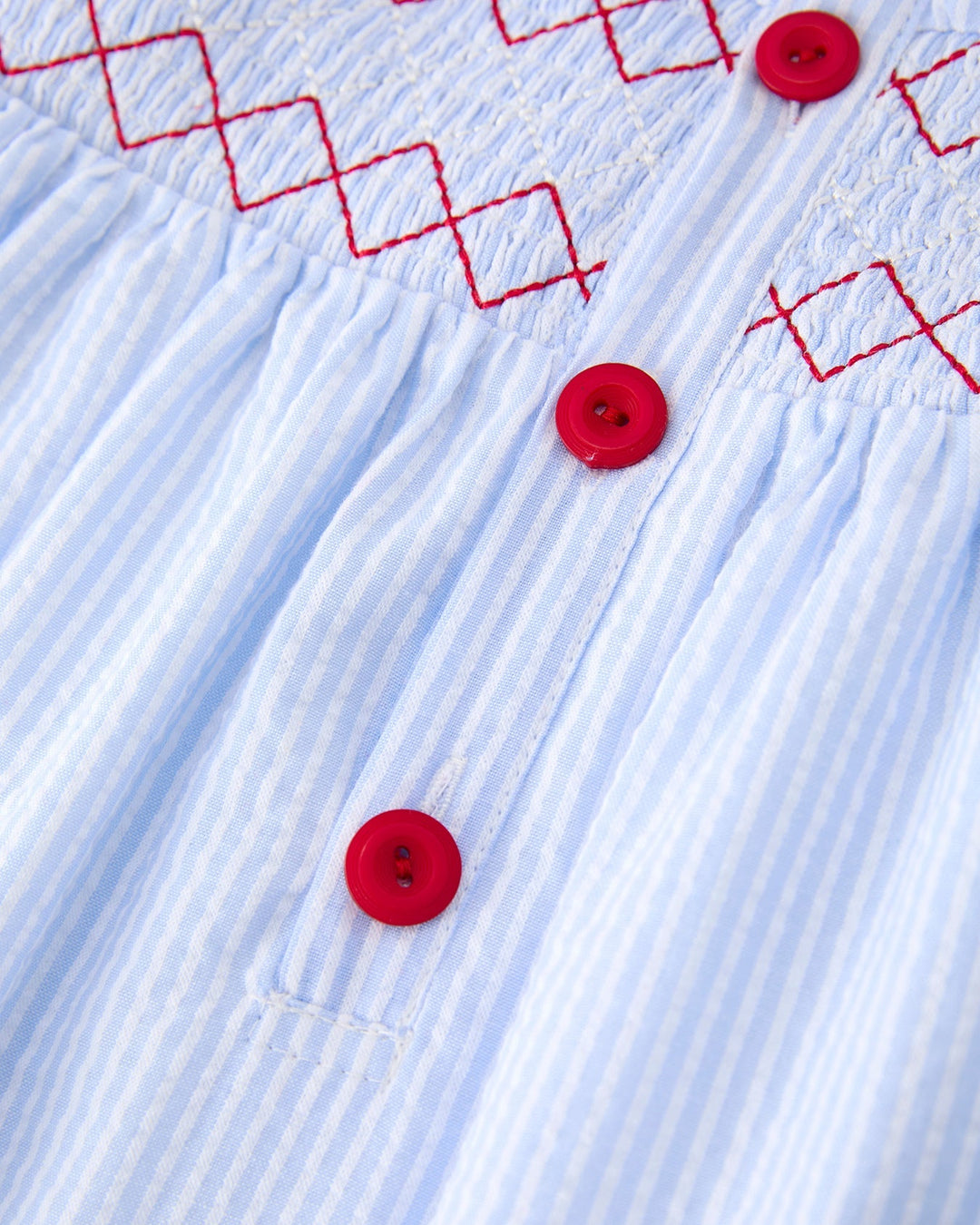 Close-up of a blue fabric with red buttons and embroidered patterns