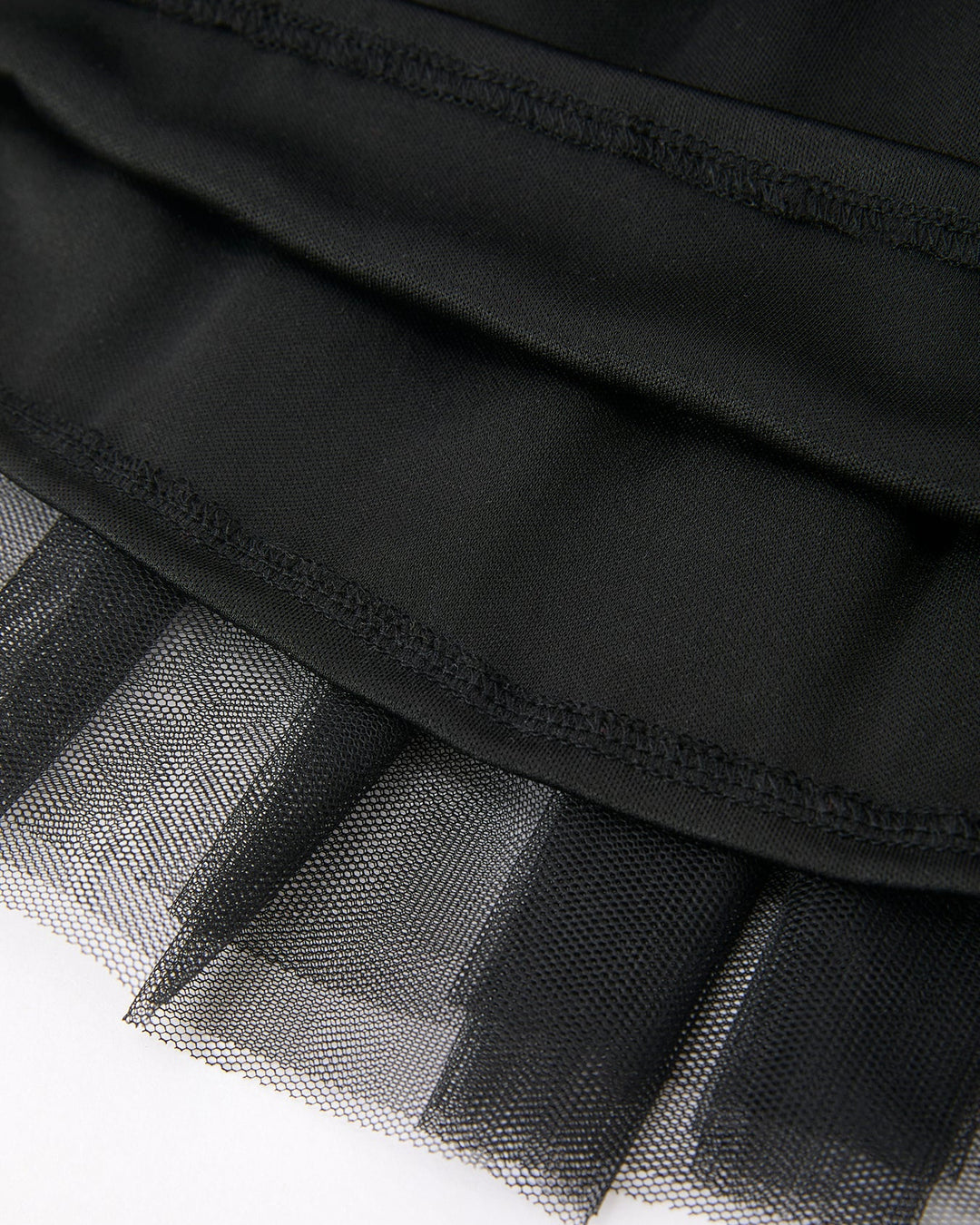 Close-up of a black tulle skirt with a plain background