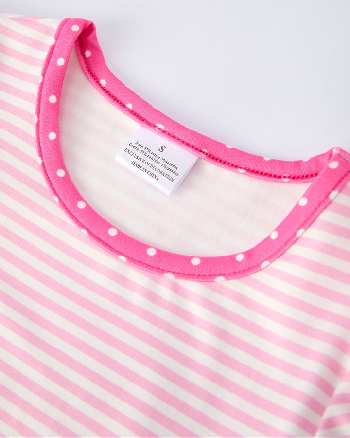 Close-up of a pink and white striped garment with a polka dot trim on a white background.
