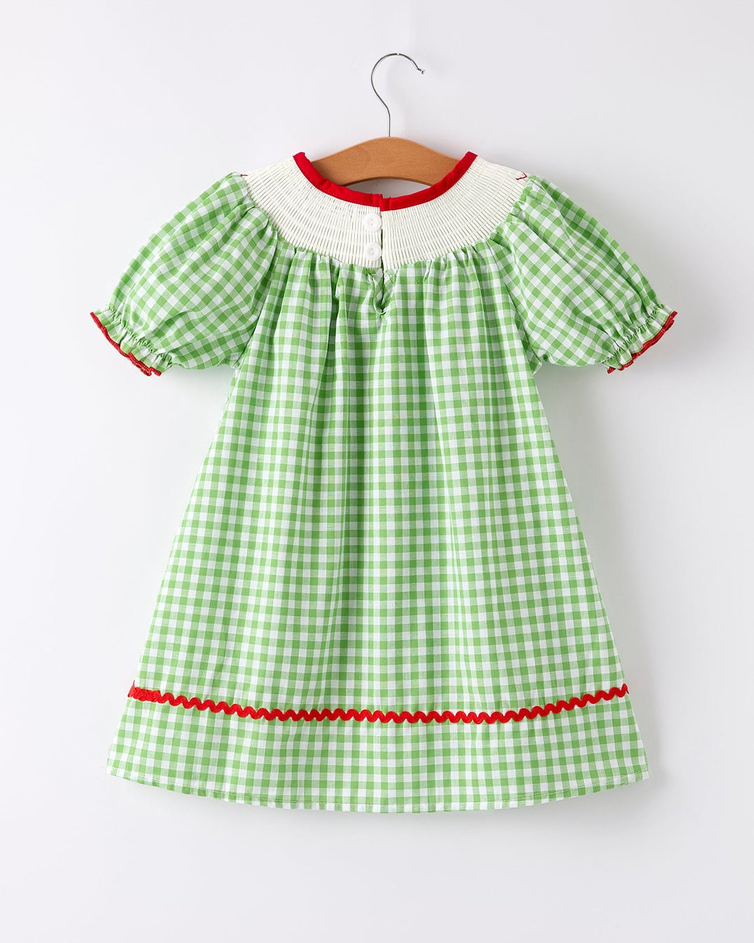 Green checkered dress with red trim on a hanger against a white background