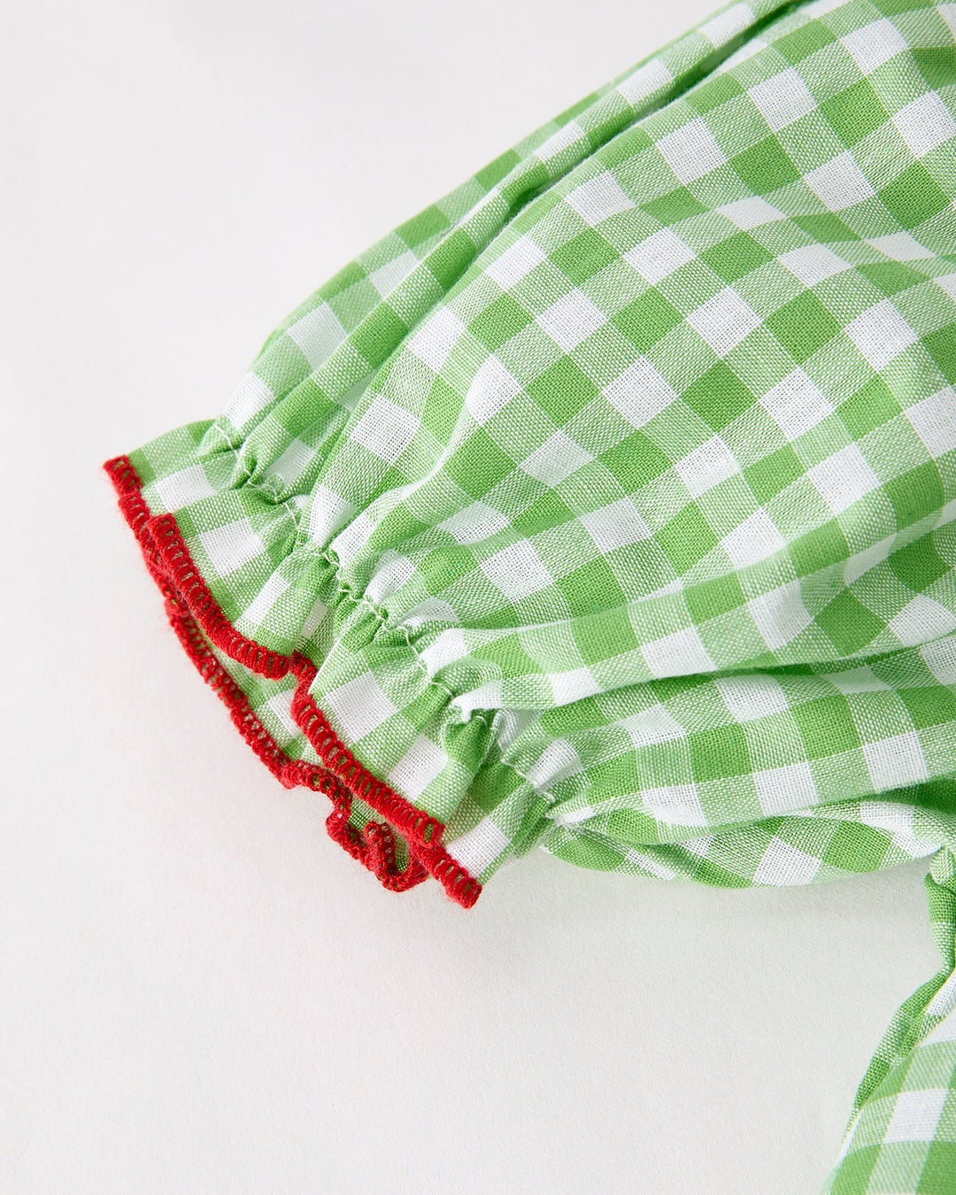 Green and white checkered fabric with red trim on a white background