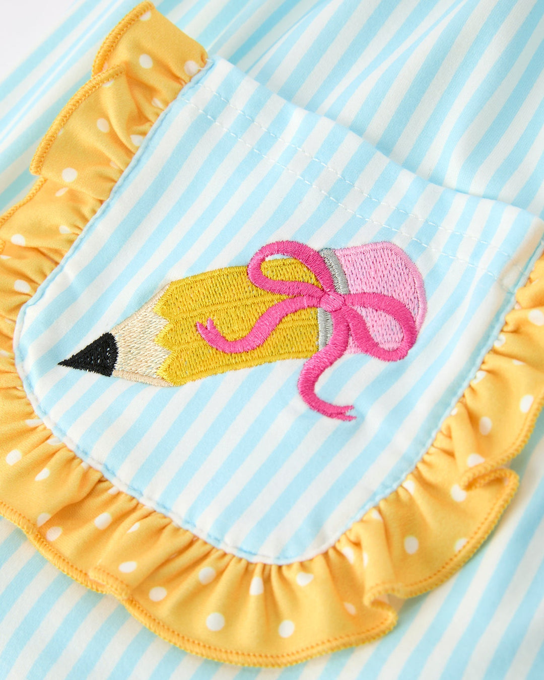 Yellow outfit with a pencil and bow design on a blue and white striped background