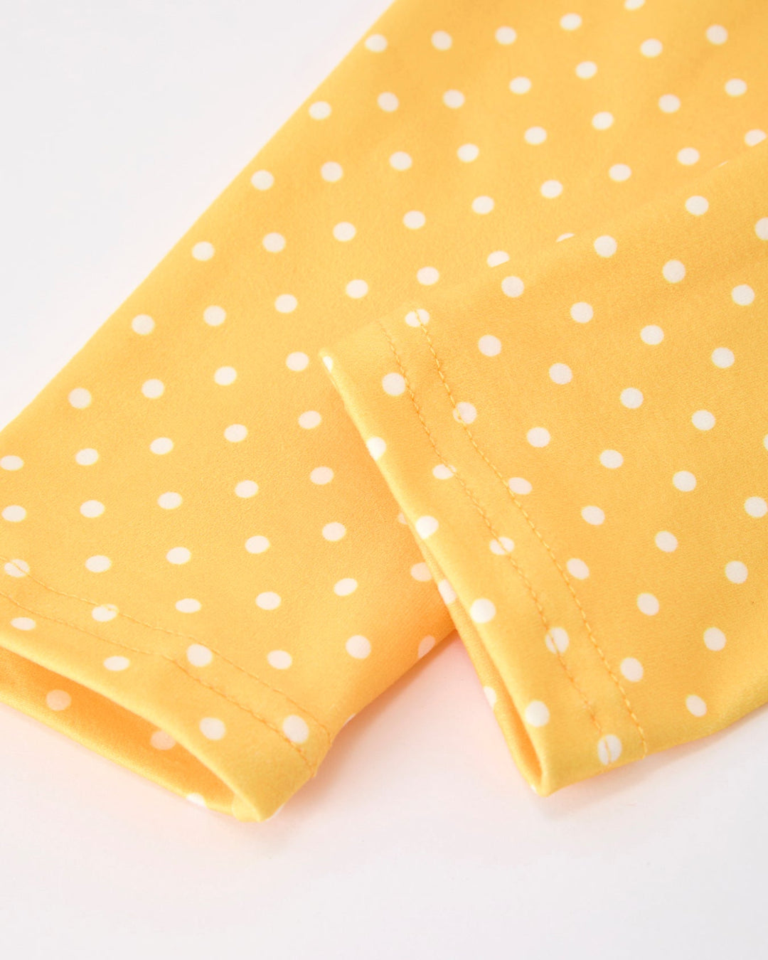 Yellow fabric with white polka dots on a white background
