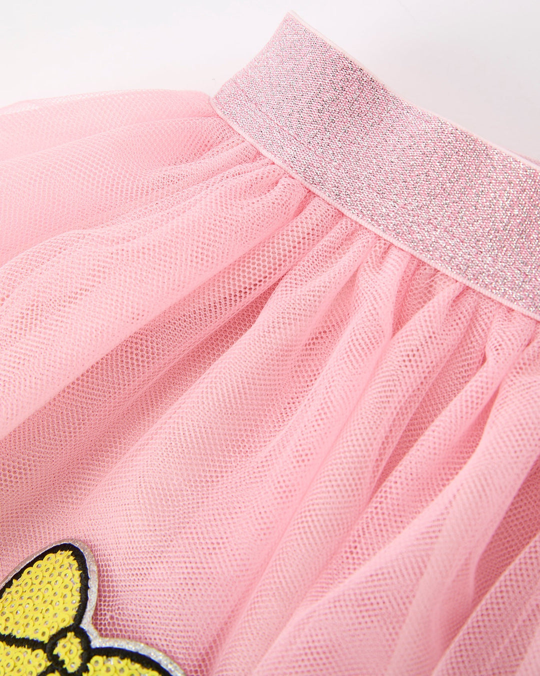 Close-up of a pink tulle skirt with a yellow bow patch on a white background