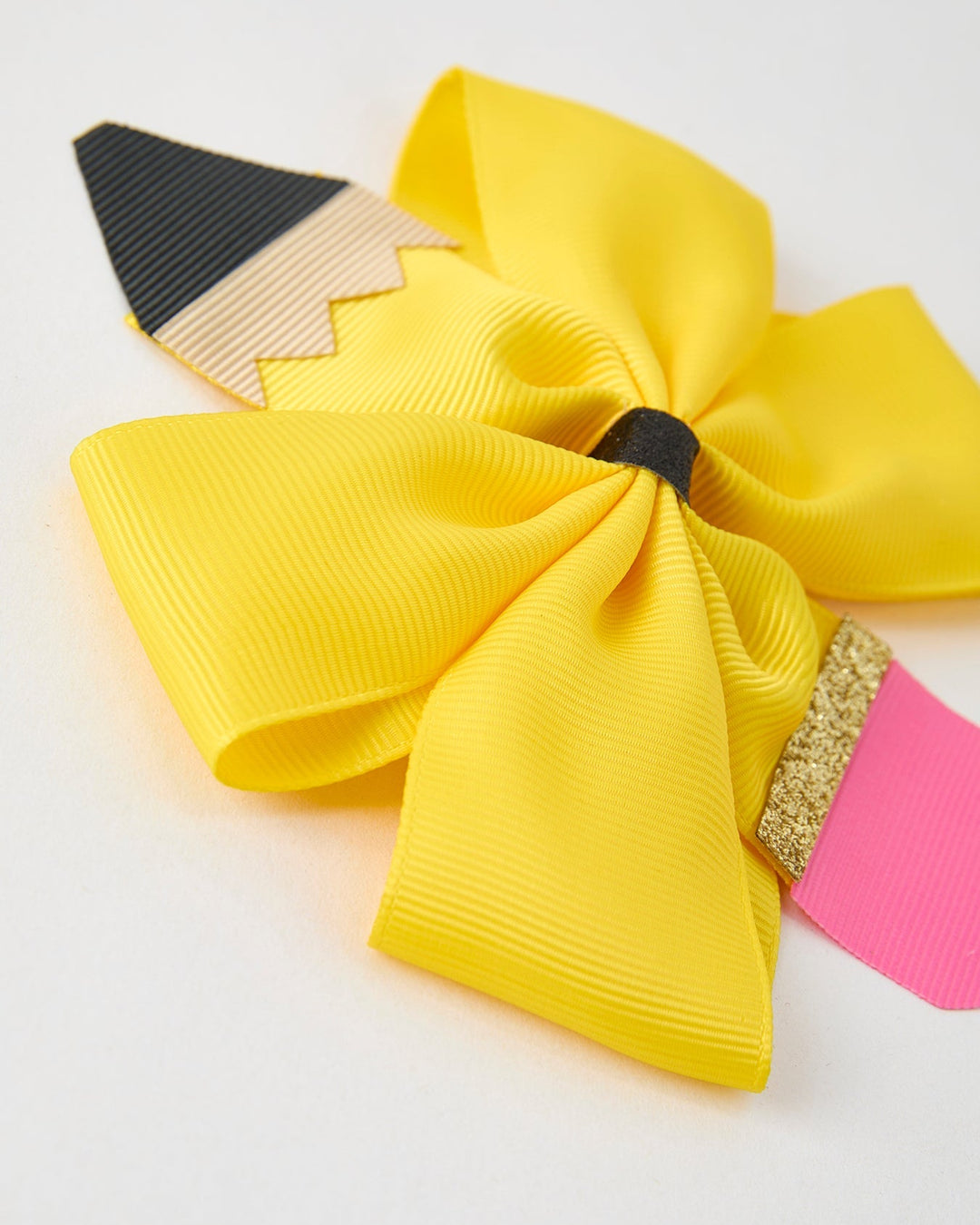 Yellow hair bow with pencil and pink ribbon on a white background
