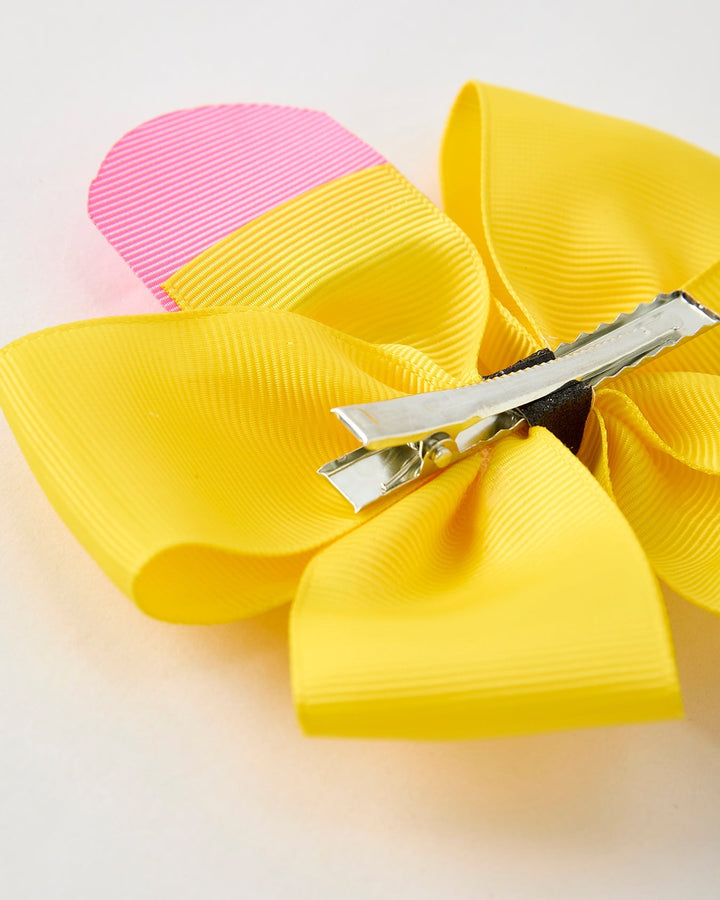 Yellow hair bow with a pink center on a light background