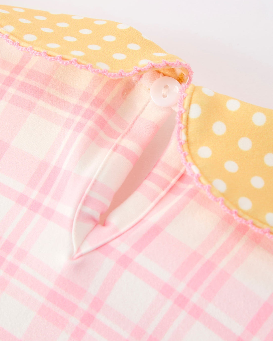 Close-up of a pink and white checkered fabric with yellow polka dot border