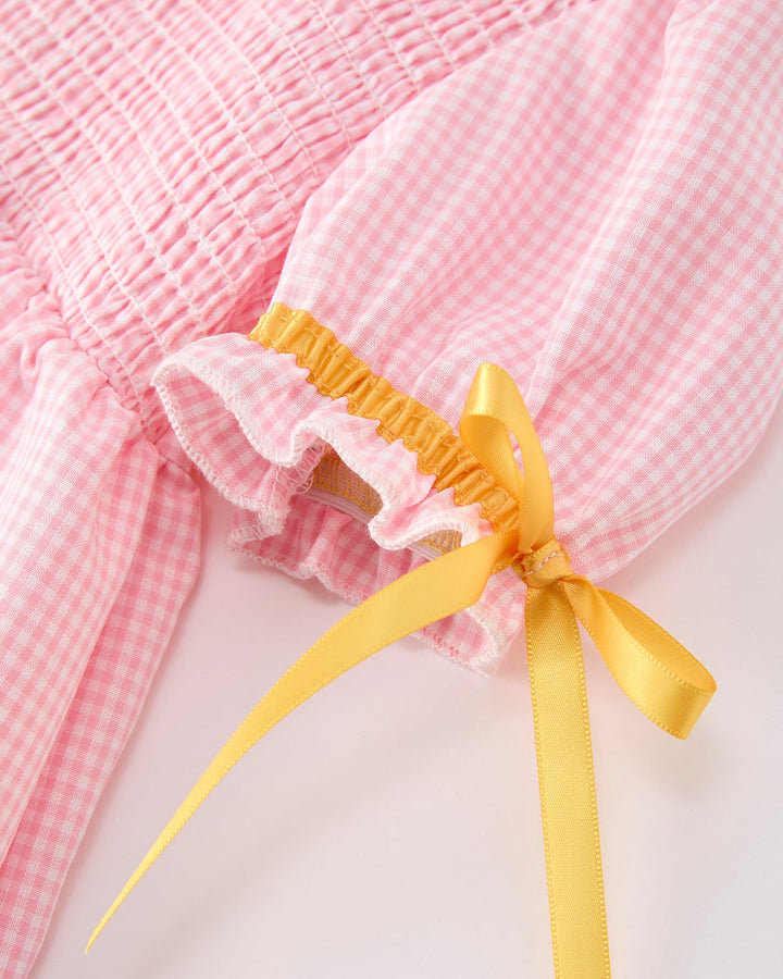 Pink checkered dress with a yellow ribbon on a light background