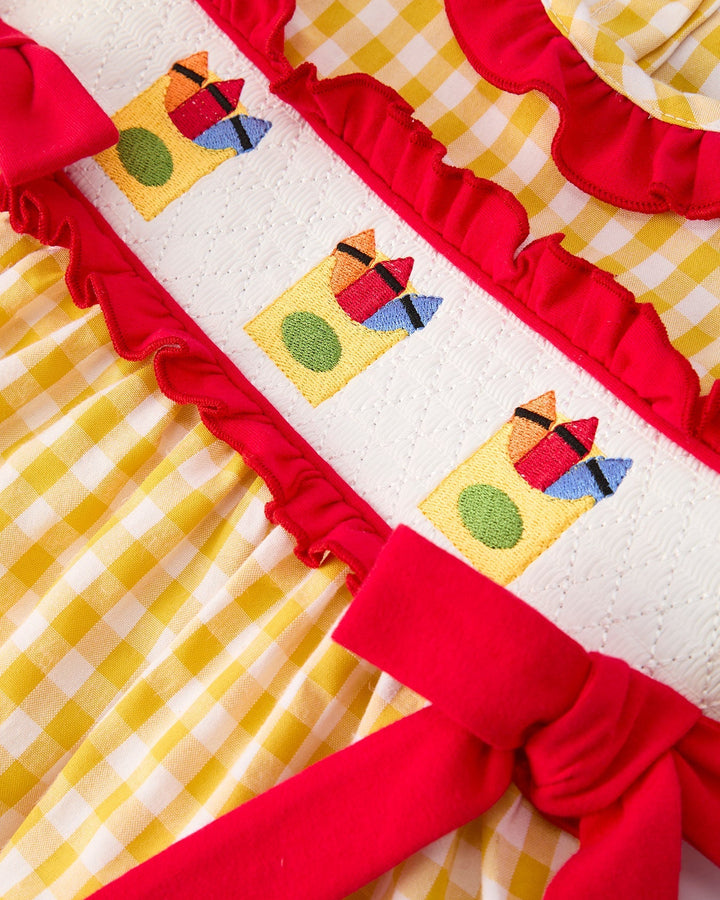 Dress with colorful appliqués and red ruffles on a yellow checkered background