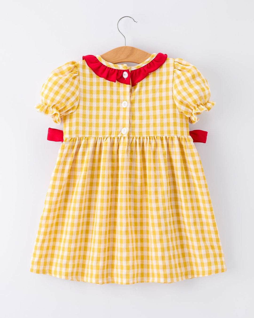 Yellow checkered dress with red trim on a hanger against a white background
