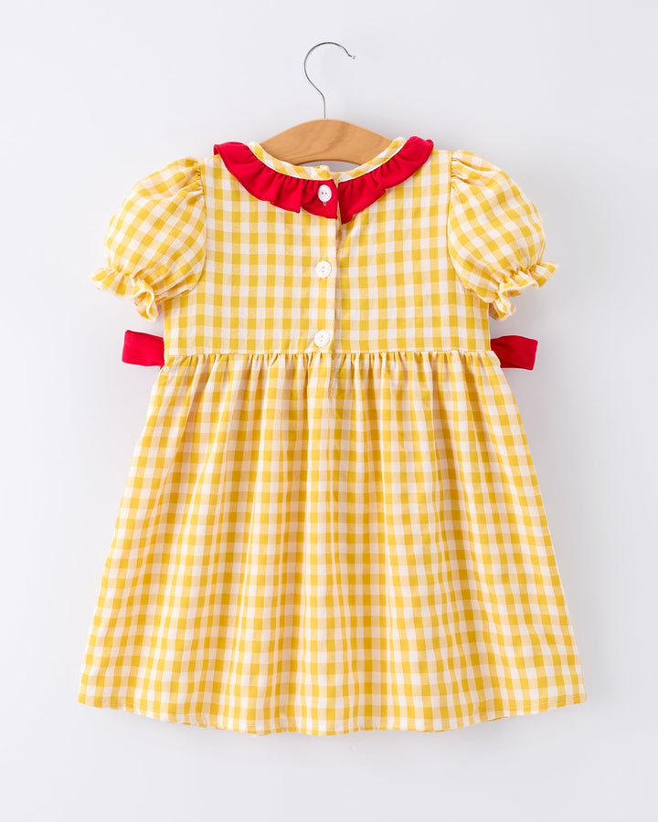 Yellow checkered dress with red trim on a hanger against a white background