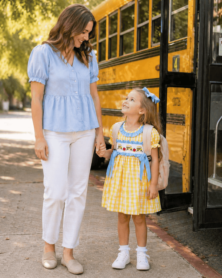 Woman and young girl standing in front of a yellow school bus
