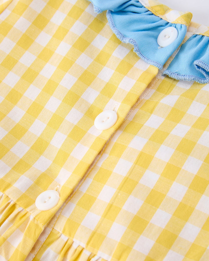 Yellow and white checkered fabric with blue trim and buttons on a matching yellow background