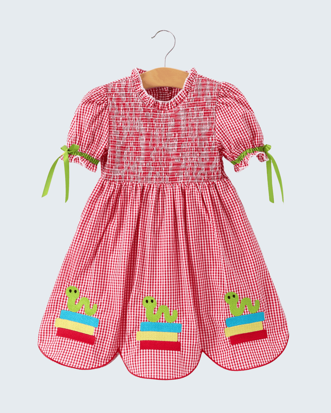 Red checkered dress with frog designs on a hanger against a light gray background