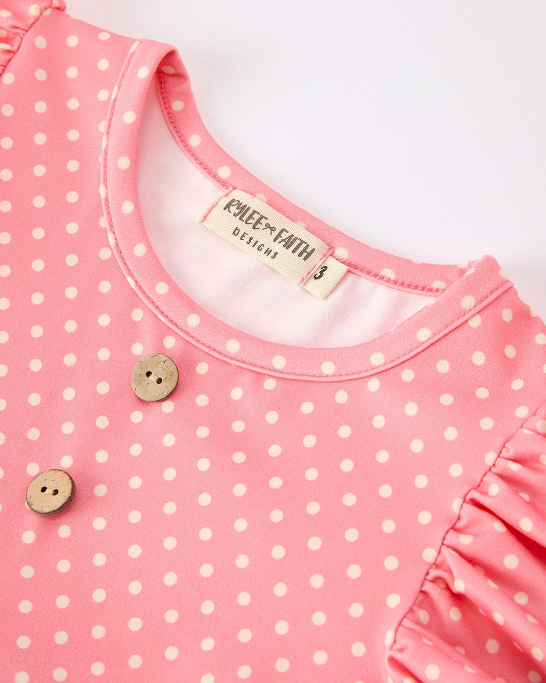 Pink polka dot dress with buttons on a white background