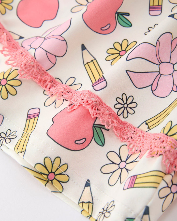 Fabric with colorful patterns including flowers, apples, and pencils on a white background.