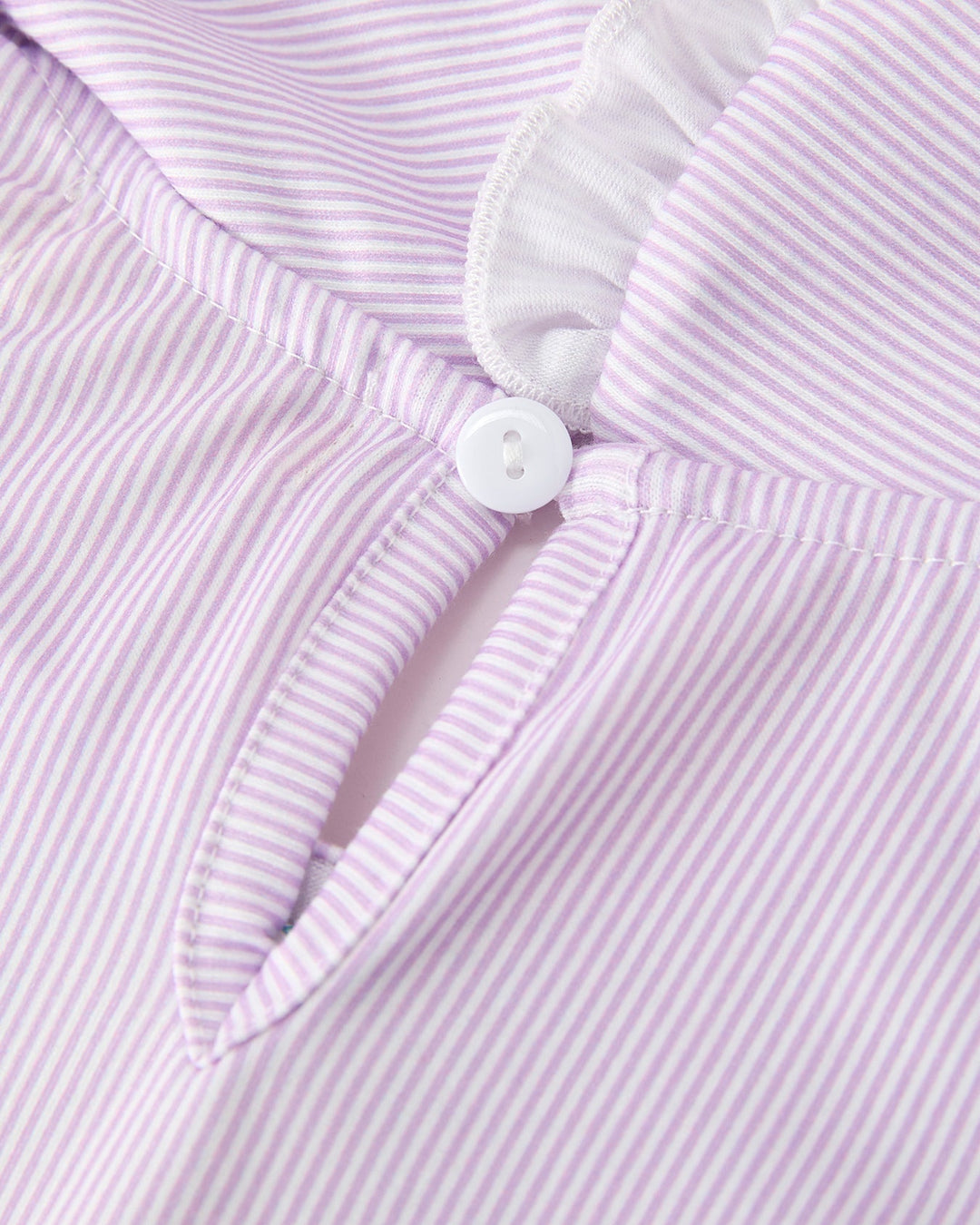 Close-up of a purple and white striped garment with a button and ruffled collar.