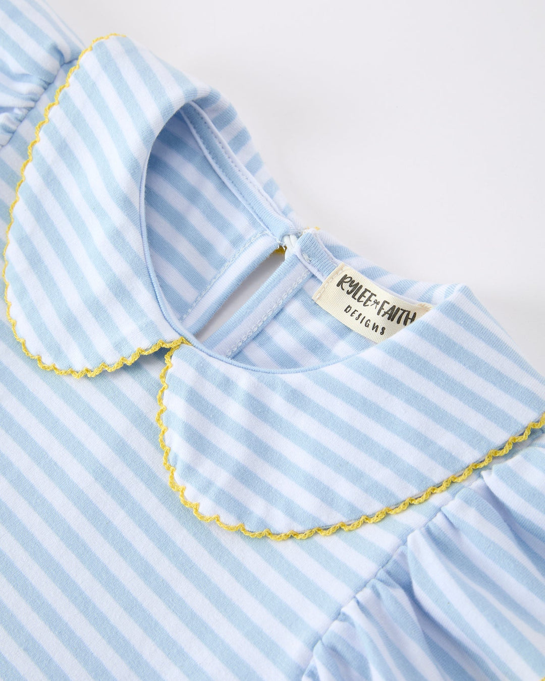 Close-up of a blue and white striped dress with a brand label on a light background