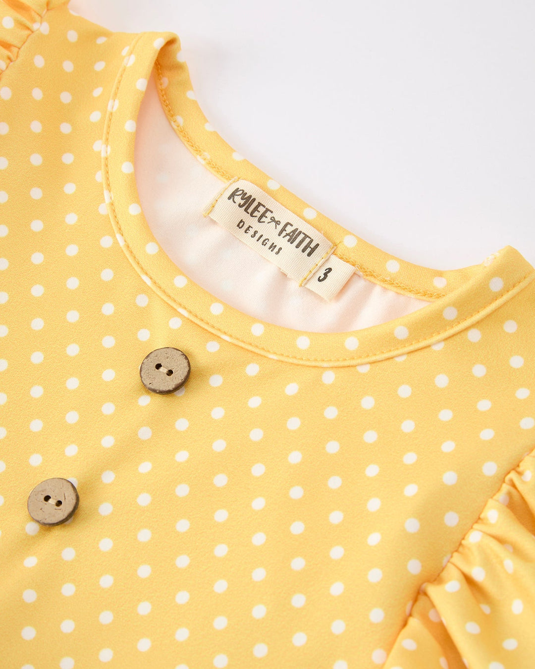 Yellow polka dot dress with buttons on a white background