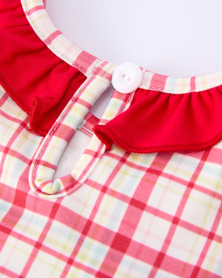 Close-up of a red and plaid fabric with a button on a white background