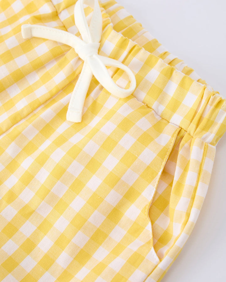Yellow and white checkered shorts with a drawstring on a light gray background