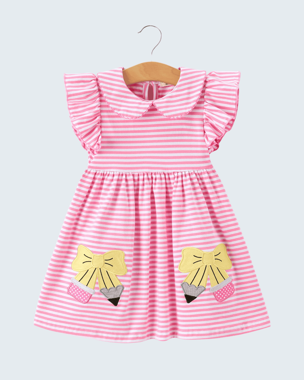 Pink and white striped dress with yellow fox appliqués on a hanger against a light gray background