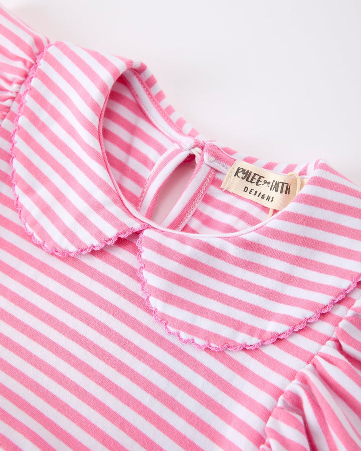 Close-up of a pink and white striped dress with a brand label on a light background