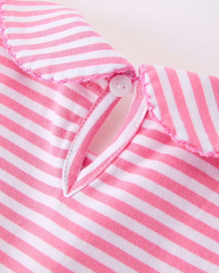 Close-up of a pink and white striped fabric with a button on a light background