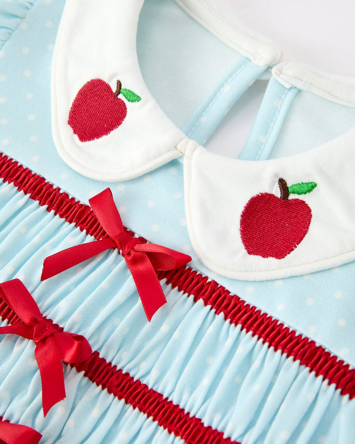 Dress with red apple design and red ribbon trim on a blue background