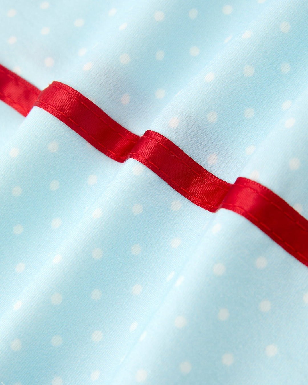 Light blue fabric with white polka dots and a red ribbon border.