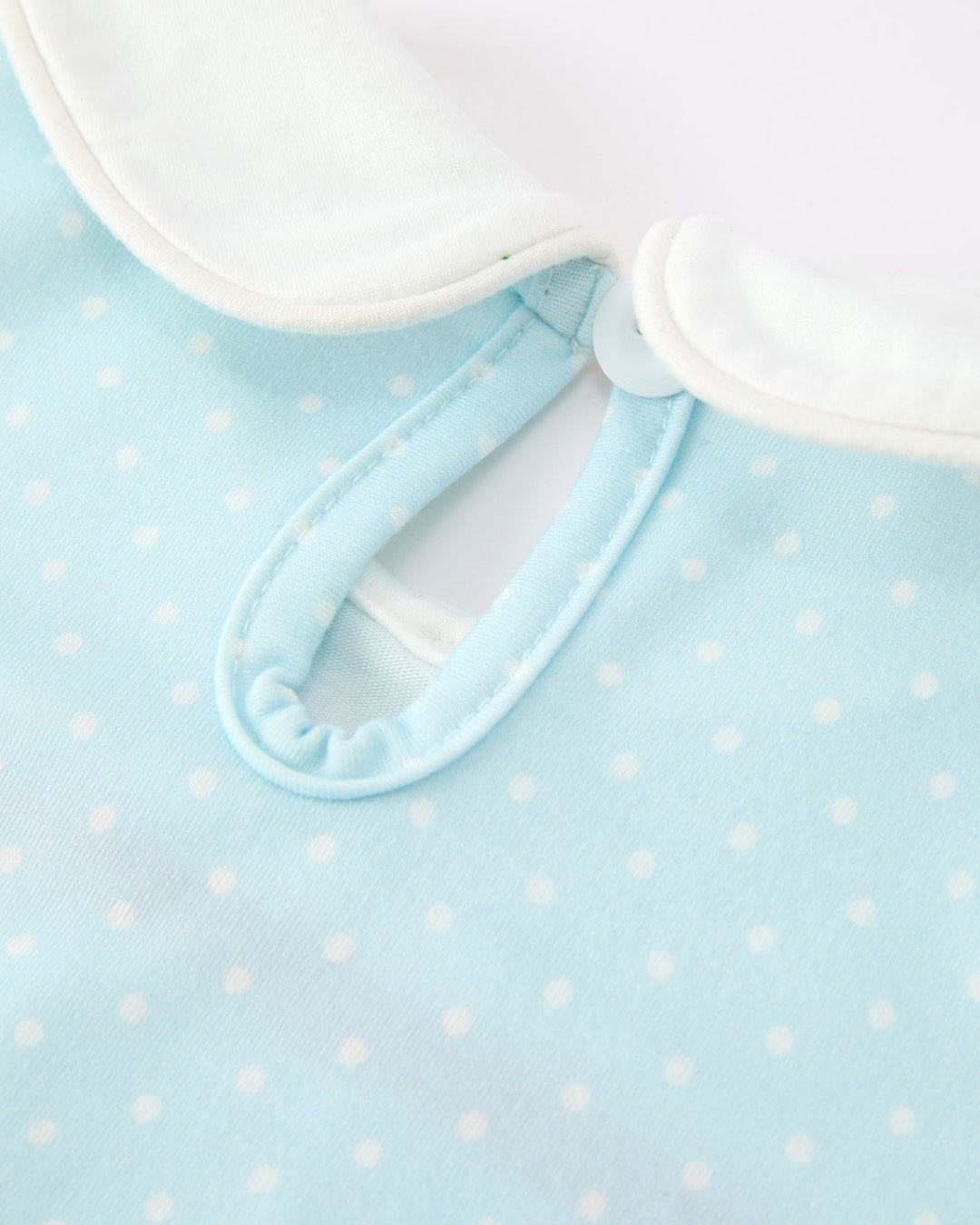 Light blue dress with white polka dots and white collar on a light blue background