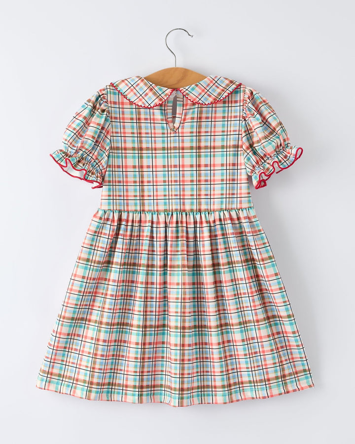 Plaid dress with ruffled sleeves on a hanger against a white background