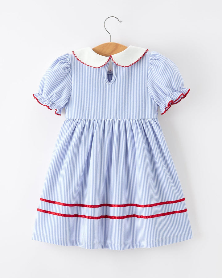 Blue and white striped dress with red trim on a hanger against a white background