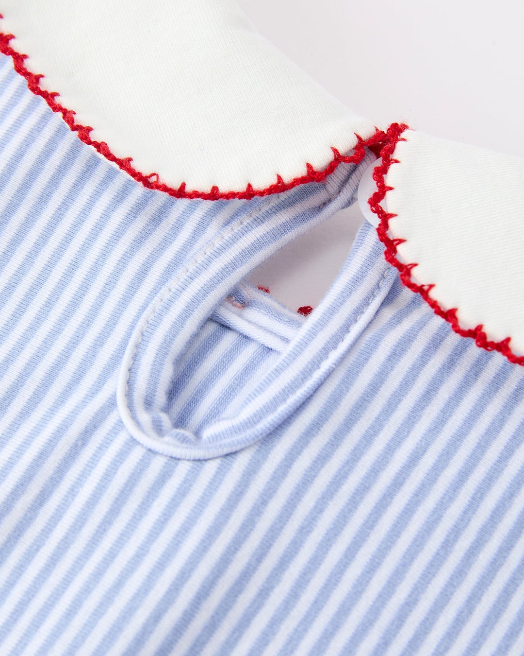Close-up of a blue and white striped garment with red trim on a white background