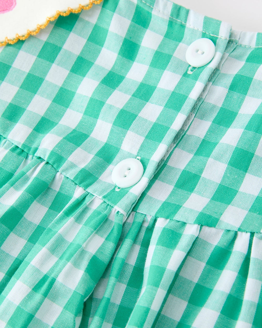 Green and white checkered fabric with buttons on a plain background