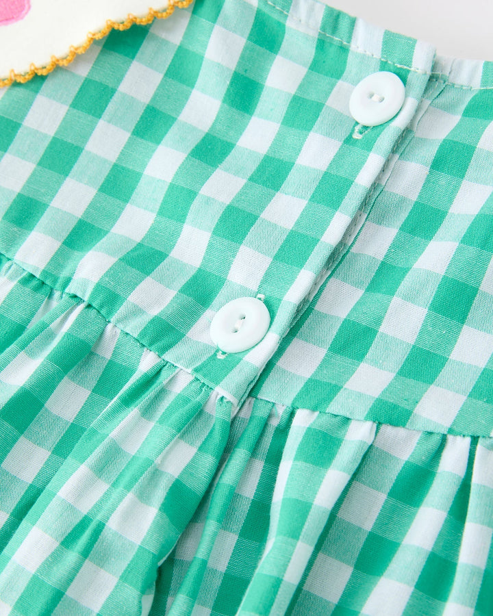 Green and white checkered fabric with buttons on a plain background