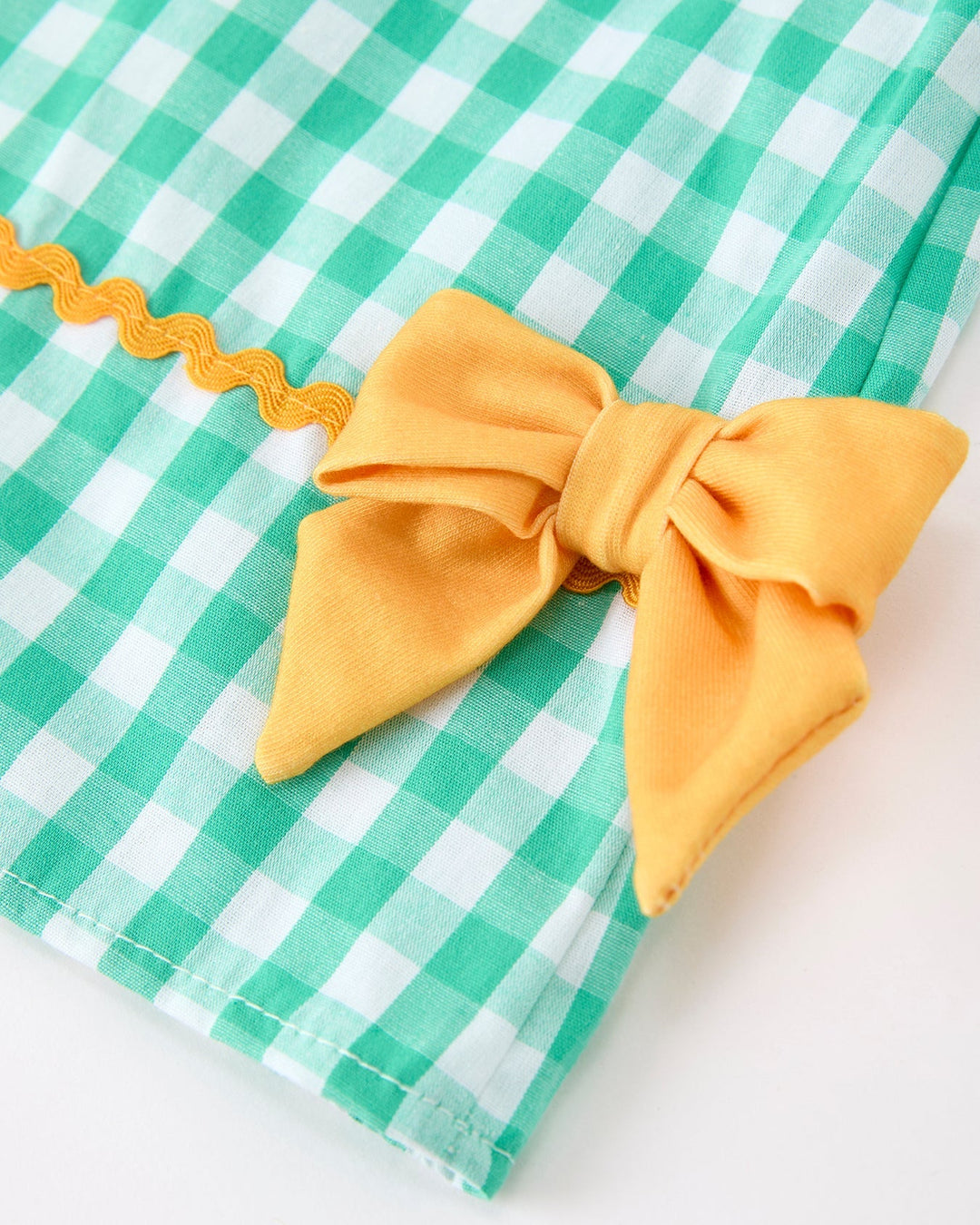 Green and white checkered fabric with a yellow bow on a white background