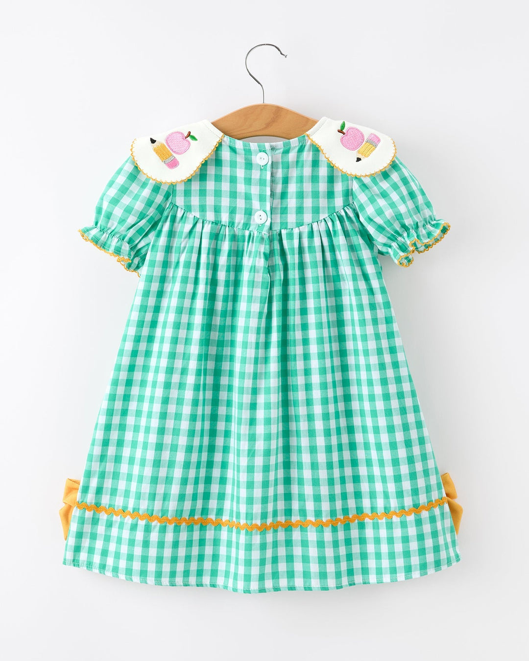 Green checkered dress with yellow trim on a hanger against a white background