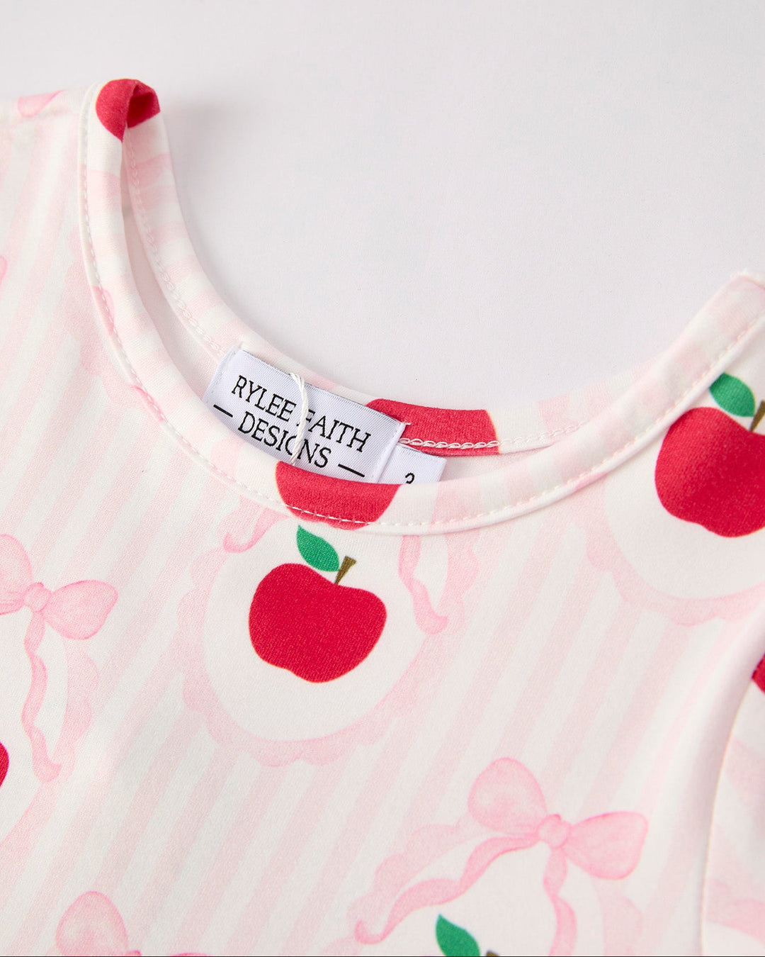 Close-up of dress with apple and bow pattern and Rylee and Cru label.