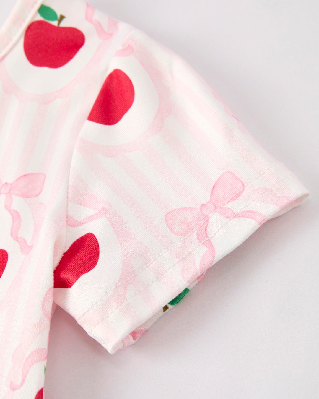 Fabric with red apple and pink bow pattern on a white background