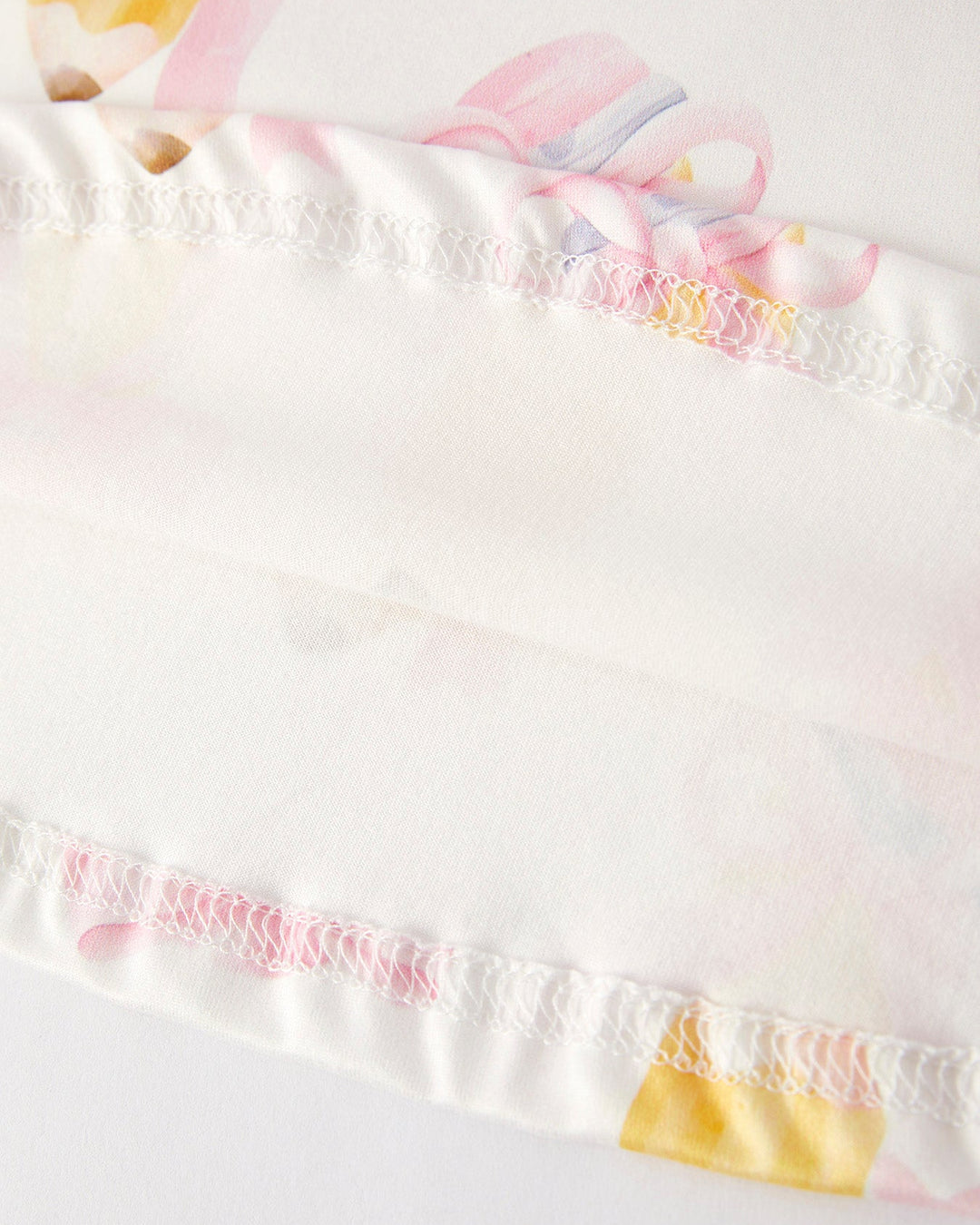Close-up of a white garment with colorful trim and patterns.