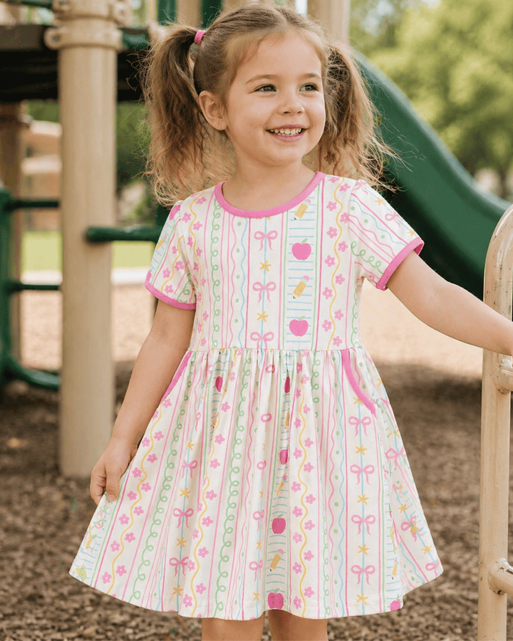 Young girl in a patterned dress standing on a playground