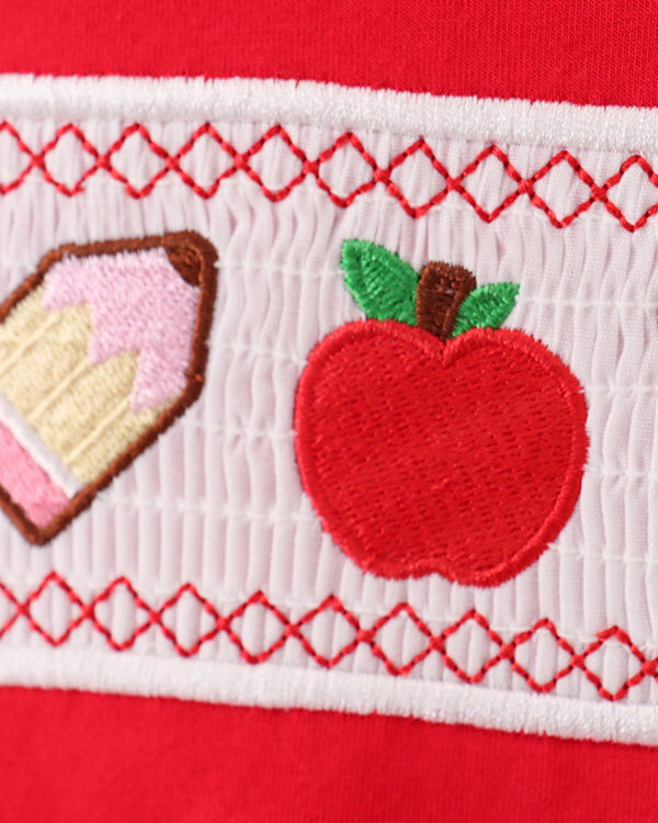Red fabric with embroidered apple and cake design on a white background