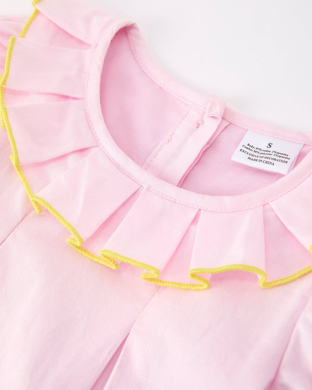 Close-up of a pink dress with yellow trim on a white background