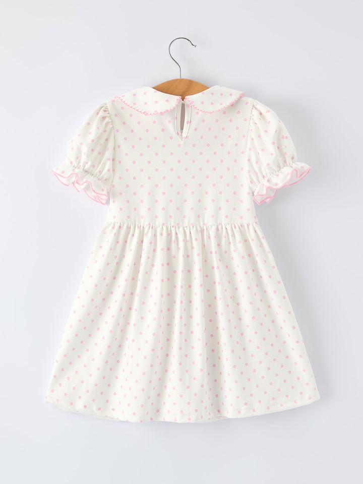 White dress with pink floral pattern on a hanger against a light gray background