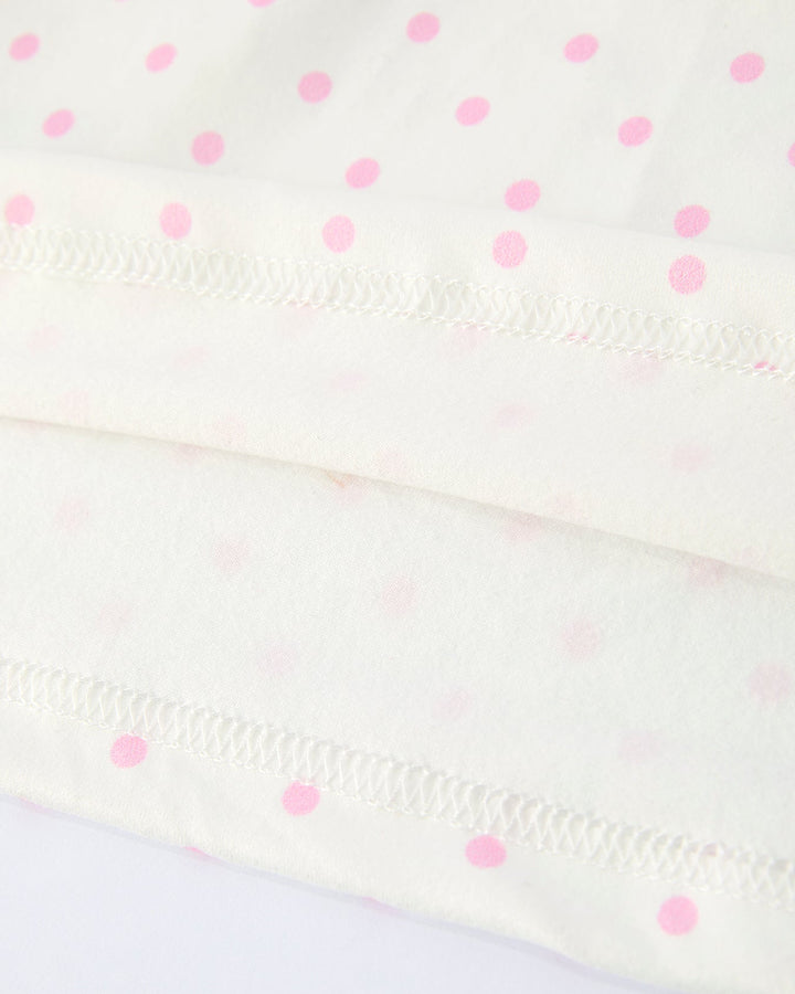 Close-up of a white fabric with pink polka dots on a light purple background